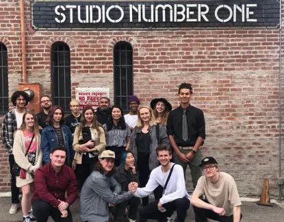 Group of art students posing in front of a brick wall